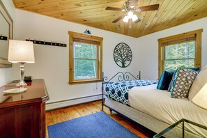 A bedroom with a bed, a desk with a lamp, two windows, and a ceiling fan. - Vermont Cabin Escape | Okemo, Hiking & Fireplace (Cavendish)