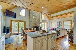A spacious kitchen with granite countertops, wooden cabinets, and a stone fireplace.