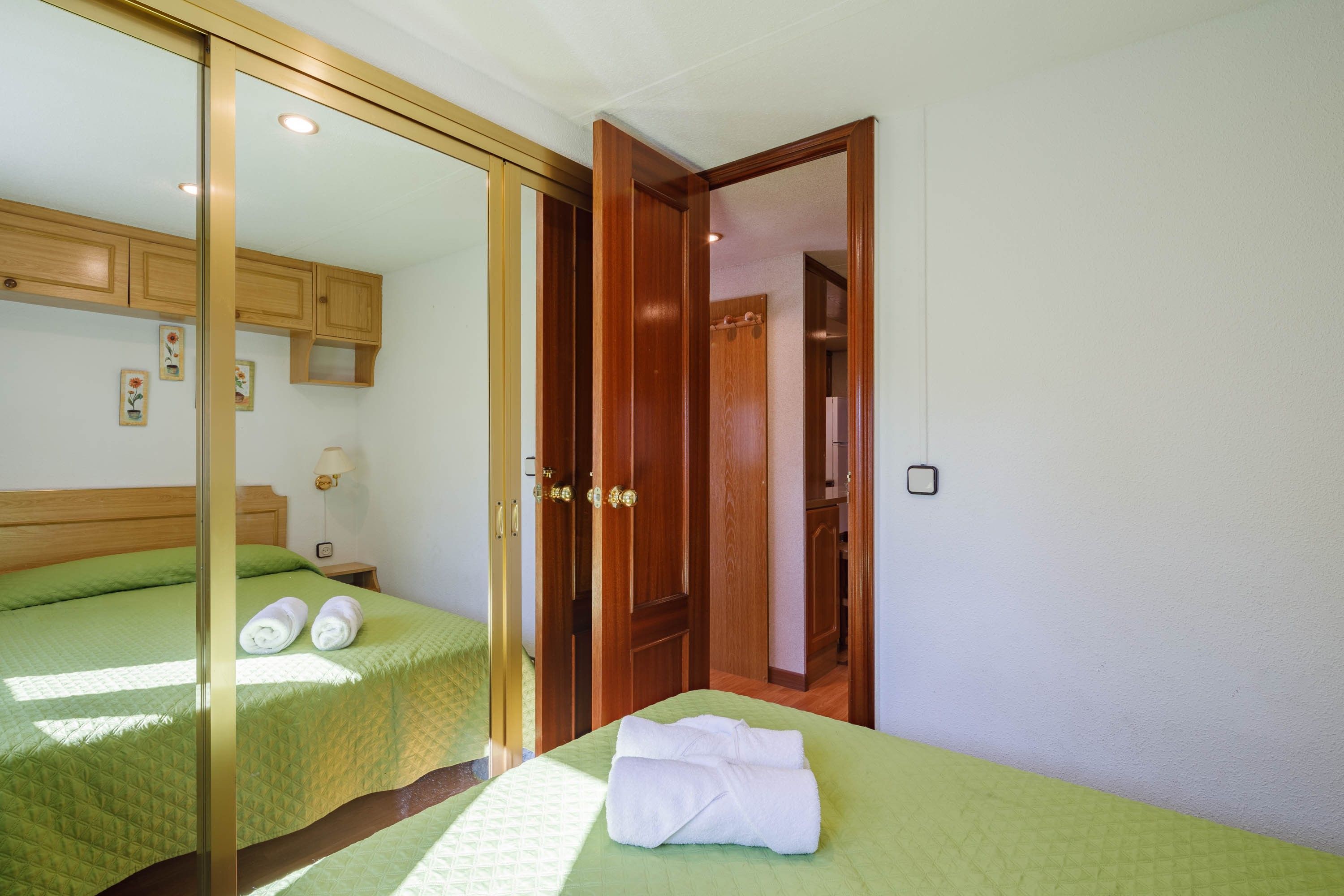 Ein Hotelzimmer mit Bett, Nachttisch, Lampe und Kleiderschrank.