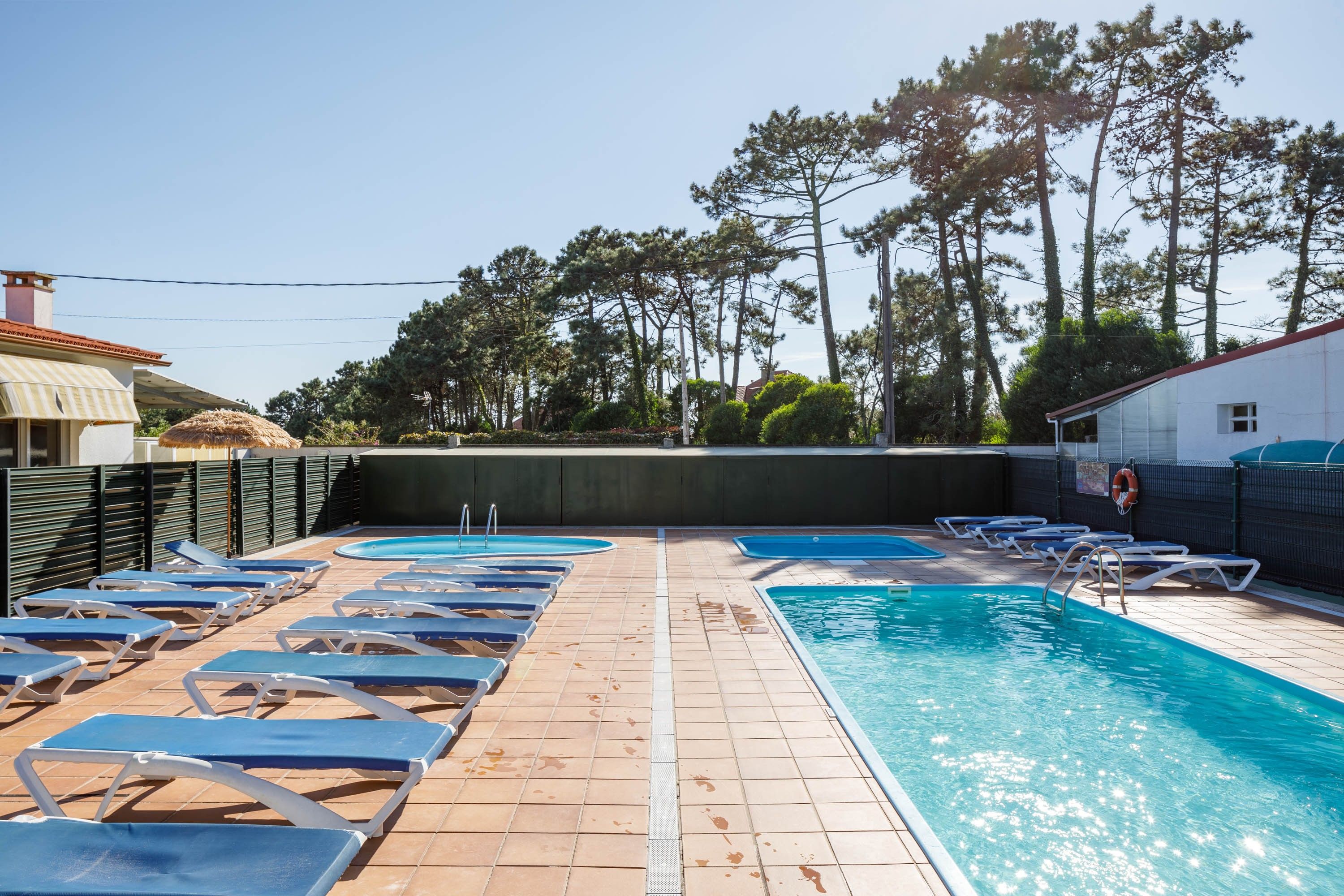 Una piscina con tumbonas y un solárium con baldosas.