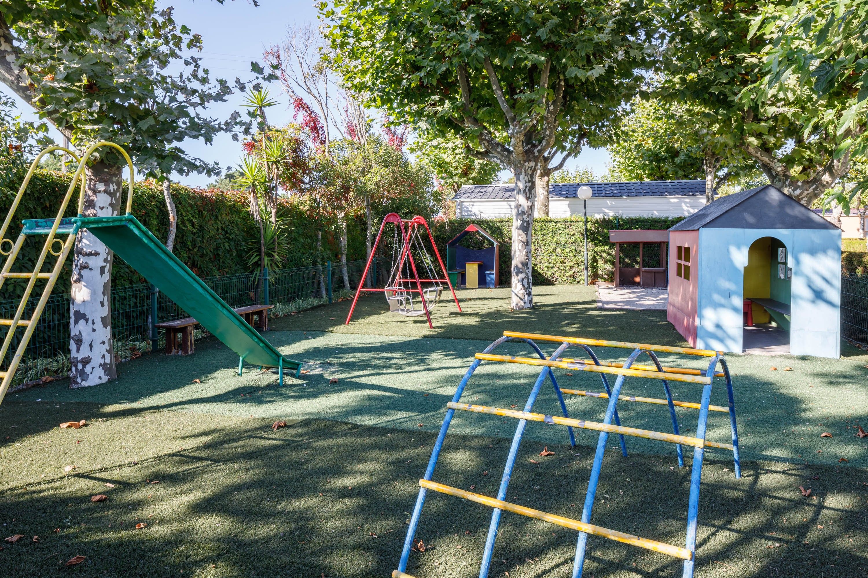 Ein Spielplatz mit Rutsche, Schaukeln und Klettergerüsten.