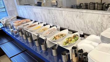 Montaje de bufé con diversas opciones de comida y utensilios de servicio.