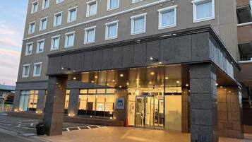 Un hotel de varios pisos con fachada moderna, un amplio acceso de vidrio y un vestíbulo bien iluminado.
