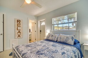 Ein Schlafzimmer mit einem Bett, einem Deckenventilator, einem Fenster mit Jalousien und einer Tür mit dem Schild 'RELAX'.