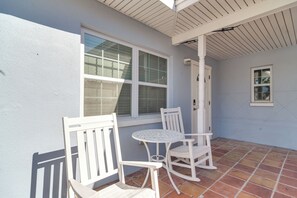 Eine Terrasse mit weißer Möbel, einem Fliesenboden und einem Fenster mit Jalousien.