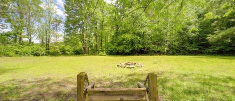 Un banc en bois, situé dans un espace verdoyant, avec des arbres en arrière-plan.