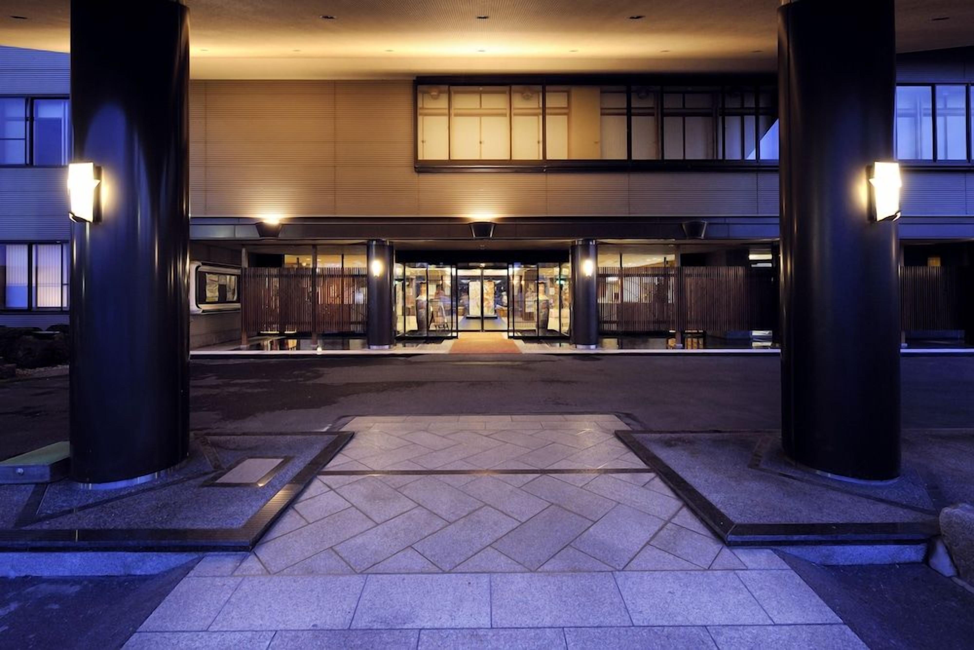 A hotel entrance with a tiled walkway, large pillars, and a double door entrance.