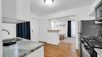 A modern kitchen with a granite countertop, stainless steel appliances, and a wooden floor.