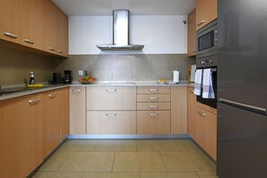 A modern kitchen with wooden cabinets, a stainless steel range hood, a built-in oven, and a refrigerator. - Beautiful house at Salobre Golf Resort with private pool (San Bartolomé de Tirajana)