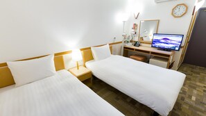 Habitación de hotel con dos camas individuales, un escritorio con computadora, un reloj y un espejo en la pared.