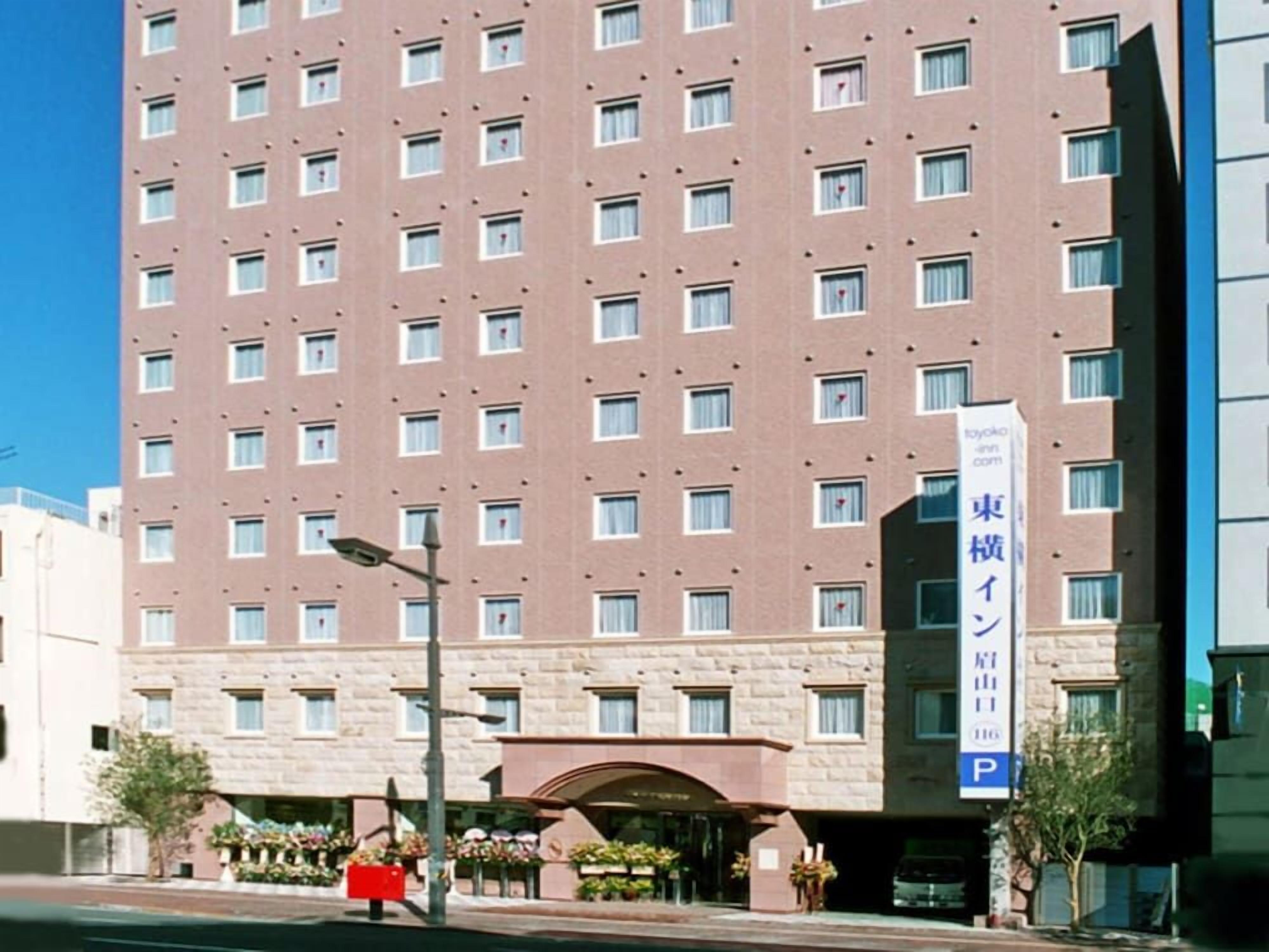 Ein mehrstöckiges Hotel mit einheitlicher Fassade, einem sichtbaren Eingang mit Vordach und einem Parkschild.