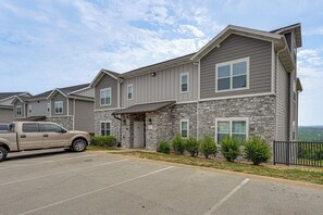 A multi-story building with a stone facade, a parking lot, and a parked truck. - Spacious Condo with Spectacular Views (Branson)