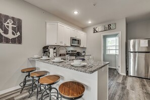 A modern kitchen with white cabinets, a granite countertop, a stainless steel refrigerator, and a coffee bar. - Spacious Condo with Spectacular Views (Branson)