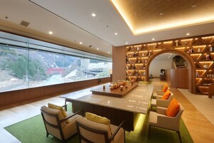 Un interior moderno con un gran ventanal, una isla central con asientos y una pared con estanterías.