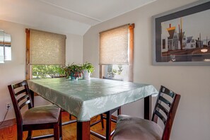 A dining area with a table covered by a patterned tablecloth, surrounded by wooden chairs with cushioned seats. - Walk to Beach! Wareham Getaway w/ Patio (Wareham)