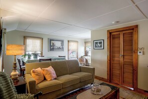 A living room with a sofa, a dining table, and a wooden door. - Walk to Beach! Wareham Getaway w/ Patio (Wareham)