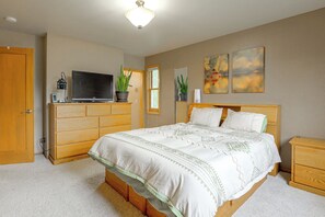 A bedroom with a bed, wooden dresser, television, and two paintings on the wall. - Riverfront Group Getaway Near Glacier NP (Columbia Falls)