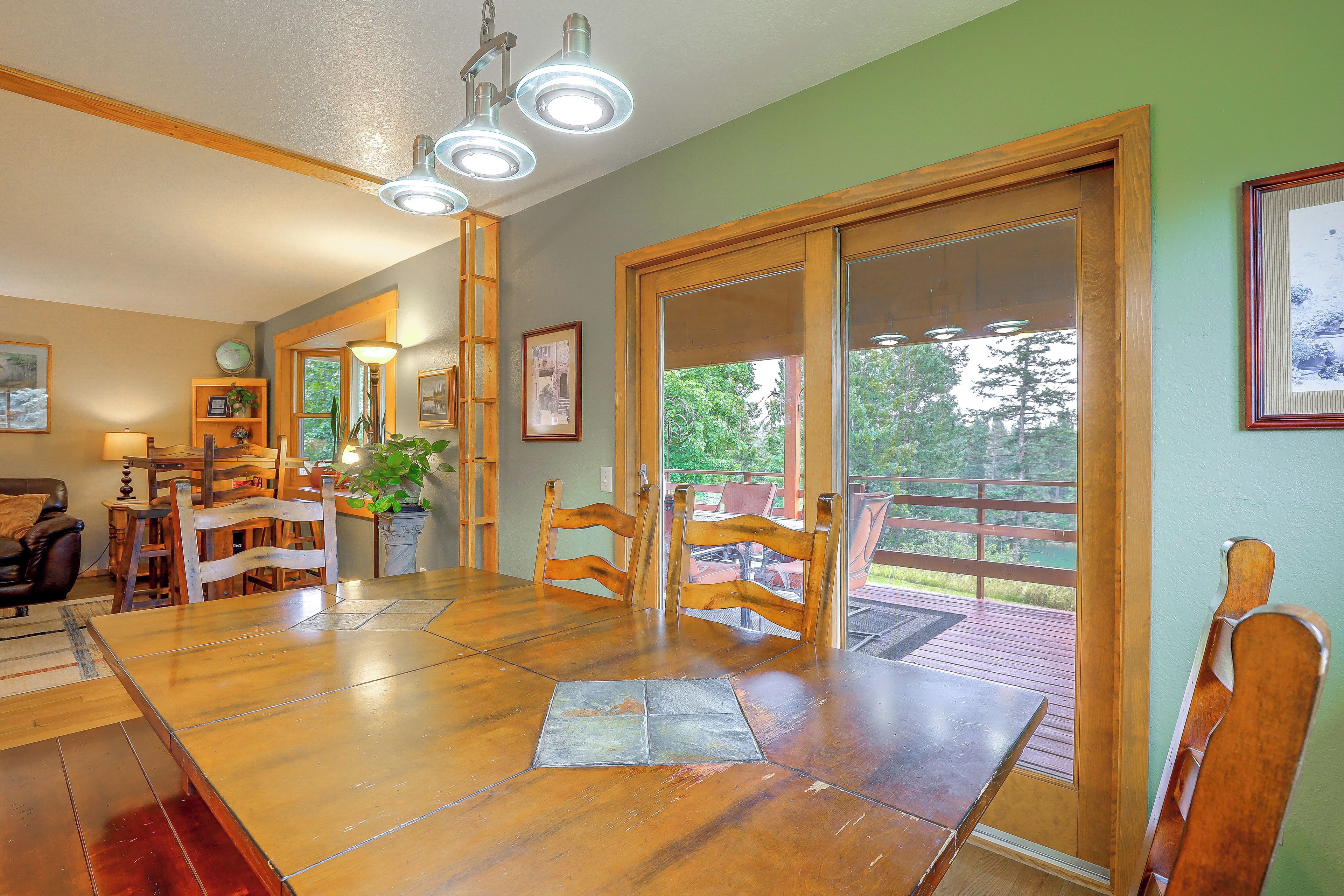 A dining area with a wooden table and chairs, a chandelier, and a view through a glass door.