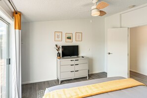 A bedroom with a bed, a dresser, a television, and a ceiling fan.
