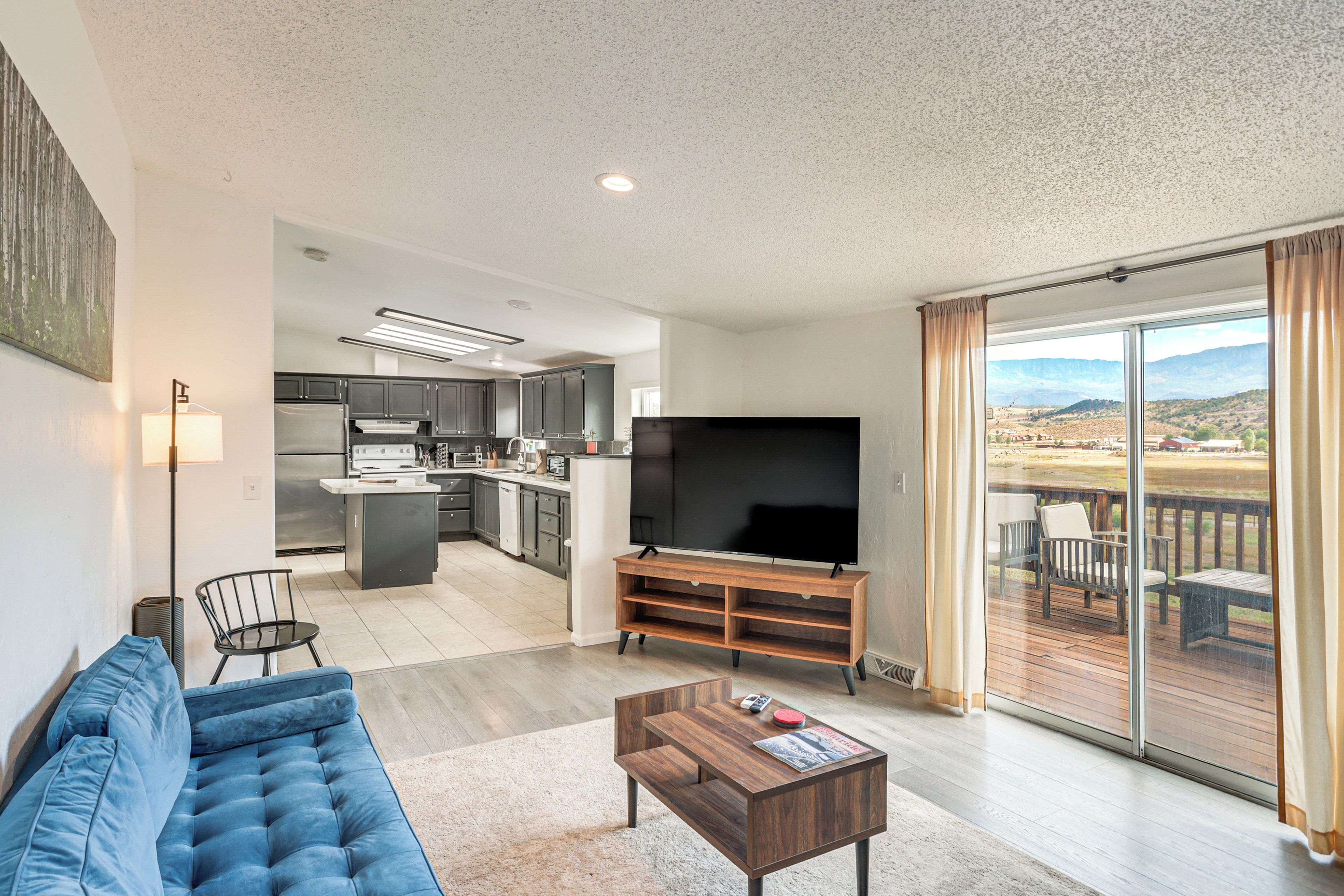 A modern living room with a blue sofa, a coffee table, and a TV on a wooden stand.