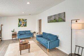 A modern living room with a blue sofa, a coffee table, and a painting of trees on the wall. - Mtn-View Colorado Escape 11 Mi to Ouray (Ridgway)