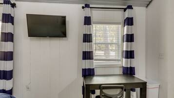 A room with a desk, chair, and a television mounted on the wall.