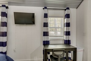 A room with a desk, chair, and a television mounted on the wall.