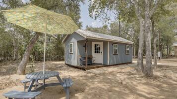 A small cabin with a porch, a table and chairs, and a patterned umbrella.