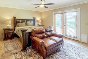 A bedroom with a bed, a leather sofa, a nightstand, a lamp, a ceiling fan, and a window with blinds. - Home w/ Fenced Yard! 2 Mi to Dtwn Casa Grande (Casa Grande)