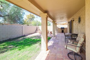 A covered patio area with outdoor seating, a barbecue grill, and a view of the backyard. - Home w/ Fenced Yard! 2 Mi to Dtwn Casa Grande (Casa Grande)