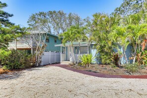 A two-story building with a balcony, surrounded by various tropical plants and a gravel driveway. - Walk to Gulf & Beaches! Indian Rocks Beach Haven (Indian Rocks Beach)