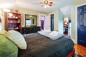 Ein Schlafzimmer mit Bett, Kommode, Spiegel und Tür.