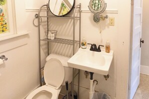 Een compacte badkamer met toilet, wastafel en spiegel.