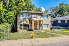 A two-story residential building with a front porch, a visible garage door, and a fire hydrant in the front yard. - Cincinnati-Area Condo: Near Shops & Dining (Cincinnati)