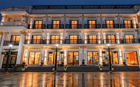 A multi-story hotel with a grand entrance, large windows, and a reflective wet ground.