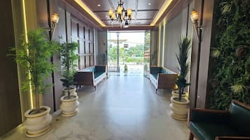A hallway with seating areas, potted plants, and a view of the outdoors.