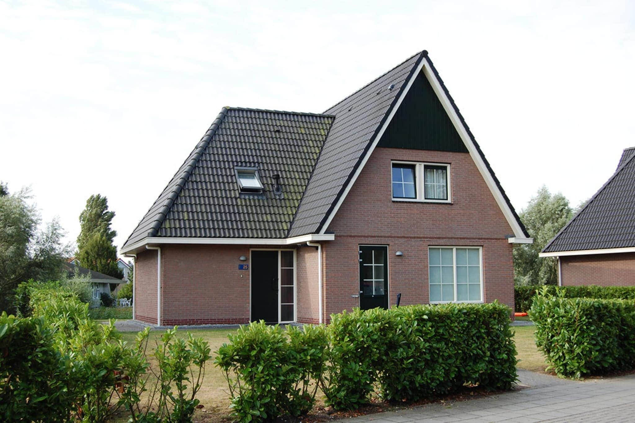 A modern two-story house with a sloped roof, a front door, and a small window.