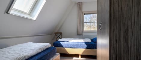 A bedroom with two beds, a window, and a wardrobe.