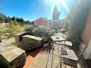 A patio area with stone walls, a wooden table, and chairs. - Naturarte (Odemira)