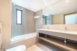 A modern bathroom with a glass-enclosed shower, a bathtub, a large mirror, and a white sink. - Bloomfields 2BR Villa in Eagle Hills  (Al-Fujairah)