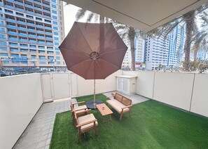 A rooftop terrace with a seating area, artificial grass, and a large umbrella. - Bloomfields 2BR Villa in Eagle Hills  (Al-Fujairah)