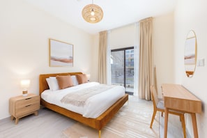 A modern bedroom with a bed, bedside table, lamp, and a view of the outside. - Bloomfields 2BR Villa in Eagle Hills  (Al-Fujairah)