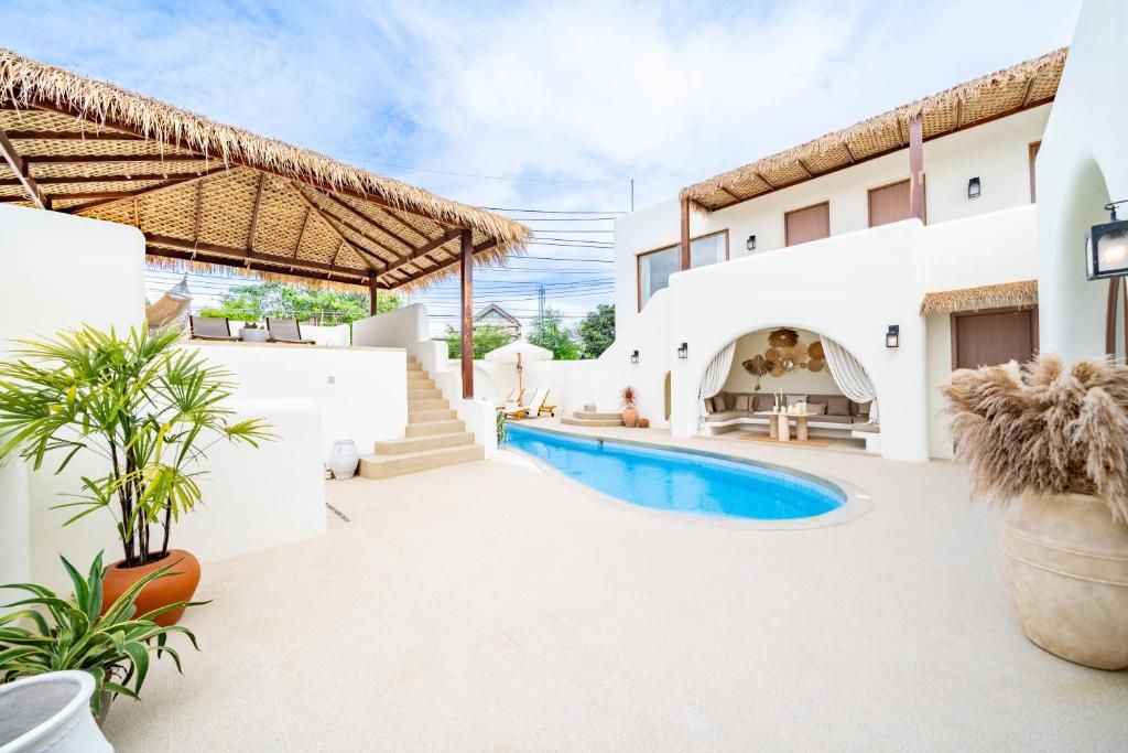 A pool area with a curved pool, a covered seating area, and a staircase leading to an upper level.