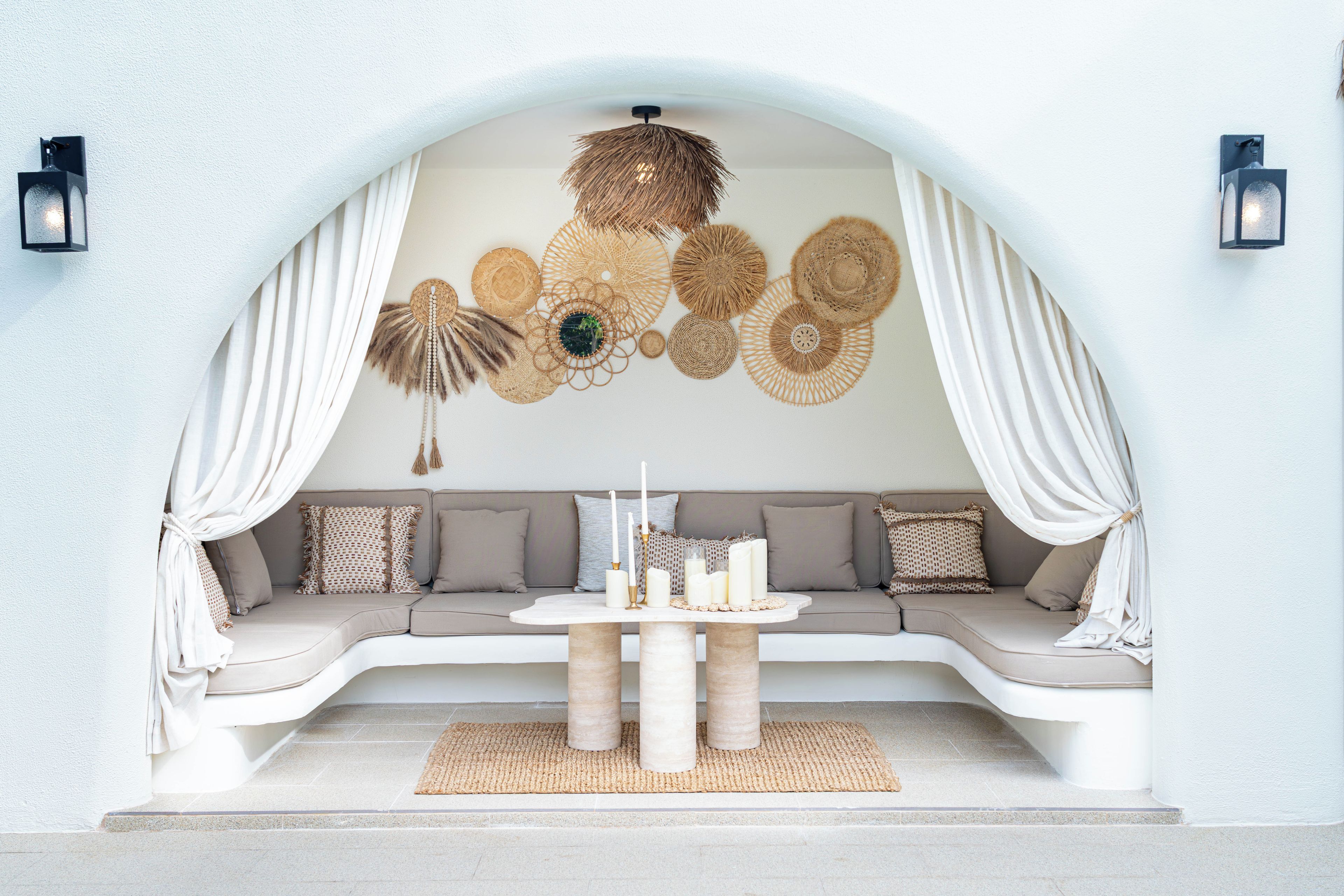 Een modern interieur met een gebogen bank, een ronde tafel met kaarsen en decoratieve wandkunst.
