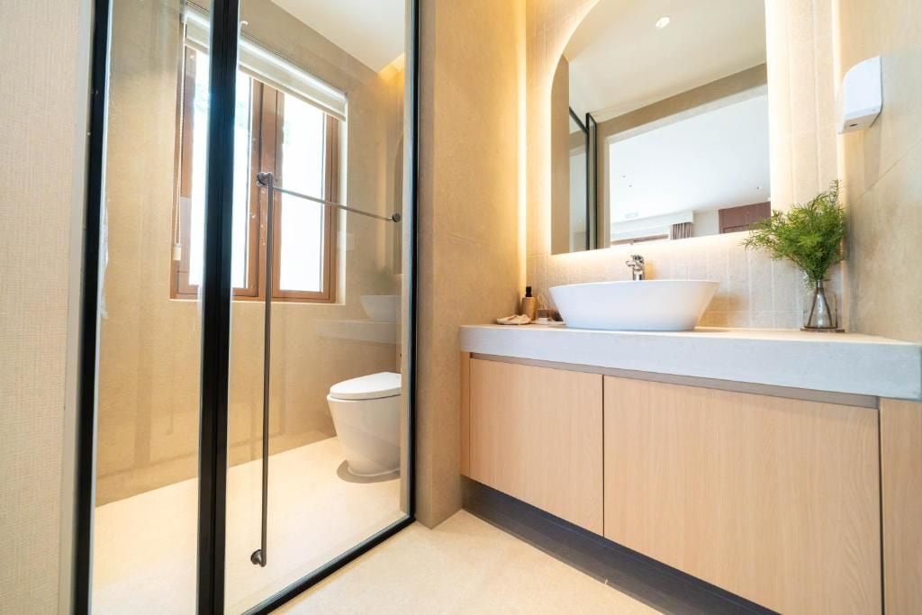 Une salle de bain moderne avec une douche à parois de verre, un lavabo blanc et un grand miroir.
