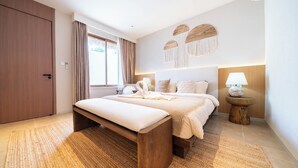 Quarto moderno com uma cama grande, um banco de madeira, uma mesa de cabeceira com abajur e luminária na parede.