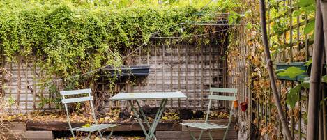A garden with a table and chairs, a brick wall, and climbing plants.