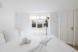 Ein heller Raum mit einem Bett, einer Heizung, einem Fenster und einer Tür.