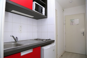 A compact kitchen with a sink, stove, and microwave. - Residence Aixoise (Aix-en-Provence)