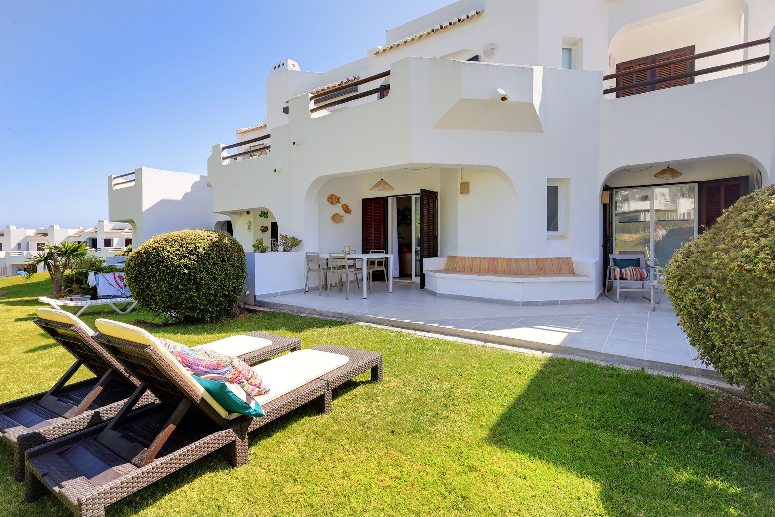 Une villa moderne dotée d’un patio, d’un espace salon extérieur et d’une pelouse bien entretenue.